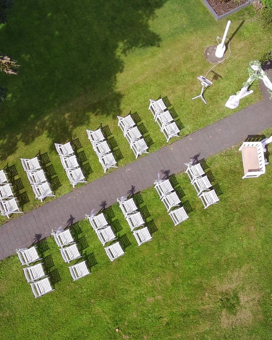 Weiße Klappstühle in Reihen am Gang, vorne die Traubank, von oben fotografiert